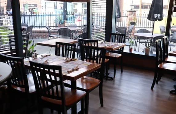 Dining room with wooden tables, chairs and front windows